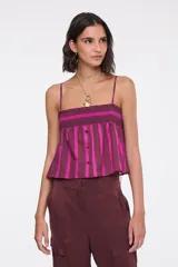 Top de algodón con diseño de rayas verticales en tonos bordó y fucsia. Presenta tirantes finos regulables, escote recto con fruncido elástico en el pecho, botones frontales decorativos y corte acampanado.