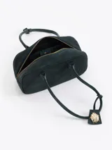 Cartera de mano de estructura rectangular, confeccionada en cuero descarne vacuno color verde oscuro. Presenta doble manija larga, cierre superior y un charm metálico dorado en forma de vaquita de San Antonio colgando de un tag lateral. Incluye el logo de la marca grabado en relieve en el frente.