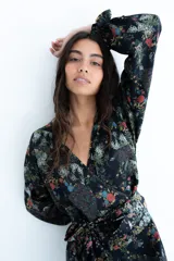 Kimono negro con estampa floral multicolor, escote en V cruzado, mangas largas con elástico en los puños y lazo ancho ajustable en la cintura.
