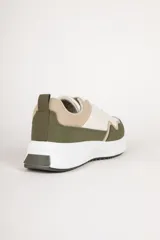 Zapatillas deportivas de gamuza color beige, con recortes en negro y marrón claro. Suela blanca de goma con base marrón.