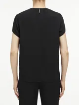 Blusa negra de poliéster reciclado con mangas cortas, cuello redondo, cierre con cremallera en la espalda y abertura en la parte delantera con barra metálica.