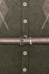 Chaqueta de punto color verde oliva con cuello redondo y manga larga. Presenta un diseño de rombos en la parte superior, cierre frontal con botones y un cinturón integrado en la cintura. Los puños y el ruedo cuentan con acabado en rib.