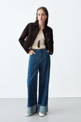Jeans de tiro alto con corte wide leg, confeccionados en denim azul. Presentan diseño de cinco bolsillos, cierre frontal con cremallera y botón, y bajo con vuelta ancha.