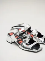 Sandalias de cuero con acabado de charol metalizado en color dorado, con tiras cruzadas en el empeine, taco cuadrado de 4,5 cm y correa ajustable en el tobillo.