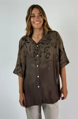 Camisa marrón con estampado animal print, cuello clásico, cierre frontal con botones y mangas cortas.