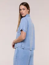 Camisa de corte recto y calce fluido color celeste, confeccionada en lyocell con efecto lavado, cuello camisero tradicional, botones a tono, dos bolsillos aplicados en el pecho y mangas cortas.