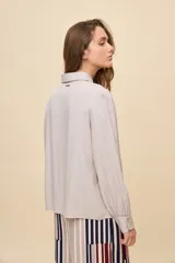 Camisa de manga larga color celeste, con cuello clásico y botonadura frontal. Presenta un calce relajado, con mangas amplias y puños anchos.