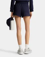 Short deportivo azul marino con cintura elástica ajustable con cordón, logo bordado en blanco y rayas laterales blancas.