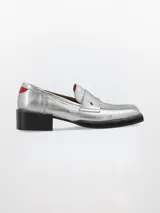 Mocasín plateado de cuero con punta cuadrada, detalle de estrella y talón en rojo.