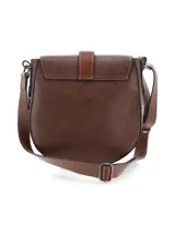 Bandolera de cuero graneado color marrón chocolate, de formato rígido y diseño con estética setentosa. Cuenta con solapa frontal con detalle de tira vertical y herraje metálico de cierre, y correa ajustable para colgar al hombro o cruzada.