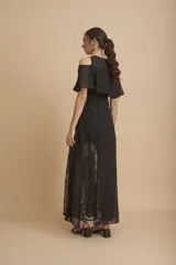 Vestido largo negro con hombros descubiertos, volados en el pecho, mangas cortas y paneles de encaje transparente en la falda.