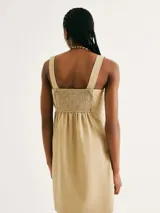 Vestido corto de color beige con escote cuadrado, tirantes anchos y corte recto con bolsillos laterales.