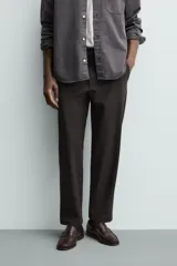 Pantalón de corte regular fit, color negro, confeccionado en tejido elástico. Presenta cintura elástica, cierre frontal con cremallera y botón, bolsillos laterales y bolsillos traseros de vivo.