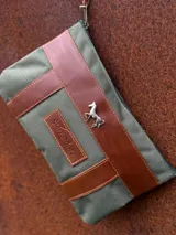 Sobre tipo cartuchera de lona con estampado de camuflaje y terminaciones en cuero marrón.