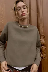 Jersey de punto liso con cuello redondo y manga larga, con detalle de costura en forma de V en el cuello.
