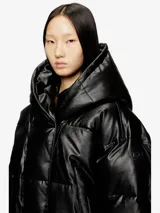Campera puffer negra de cuero sintético con capucha y diseño acolchado, corte corto y holgado, con cierre frontal y mangas largas.