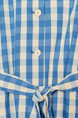 Trench largo con cuello solapa y manga larga, confeccionado en tela de cuadros vichy azul y blanco. Posee bolsillos de vivo en el delantero y un cinturón del mismo tejido para ajustar a la cintura.