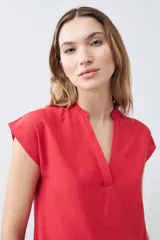 Vestido corto de color rojo con cuello en V, mangas cortas integradas y un detalle de volado en el ruedo. Presenta un diseño de silueta holgada y minimalista.