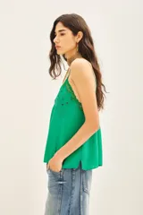 Top de crepe viscosa color verde azulado, con escote en V adornado con encaje y bordados florales con lentejuelas. Posee breteles finos regulables y elástico en la espalda.