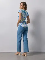 Remera color beige con estampado de hojas blancas, cuello redondo y mangas cortas.