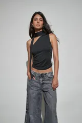 Top negro sin mangas con diseño de cuello halter y detalle de tira larga lateral. Presenta un ajuste entallado con frunces en los laterales.