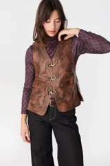 Chaleco de cuero marrón con efecto desgastado, cierre frontal mediante ganchos metálicos y bolsillos laterales con solapa y botones a presión.