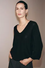 Top fluido de punto liso en color blanco, con escote en V pronunciado y mangas cortas amplias.