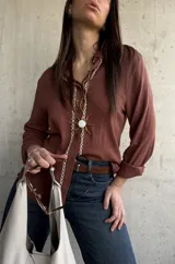 Camisa de tejido liviano y calce relajado, color marrón chocolate, con cuello mao, mangas largas y detalle de puntilla y bordado en contraste a lo largo de la botonadura frontal.