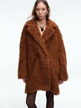 Tapado de textura tipo peluche en color marrón, con solapas anchas, mangas largas y corte holgado.