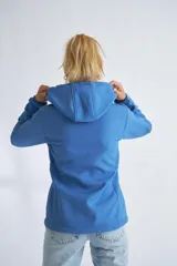 Campera de neopreno color rojo con capucha ajustable, cierre frontal completo y bolsillos laterales. Presenta puños ajustables con velcro y un parche circular decorativo en la manga izquierda.