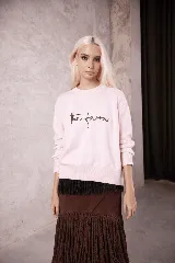 Sweater de punto color rosado con cuello redondo, mangas largas y el logo 'the farra' bordado en el frente.