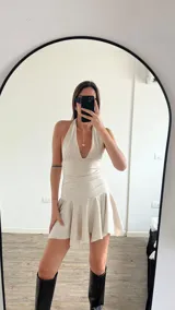 Vestido corto blanco con escote halter y falda con volados.