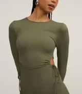 Vestido ajustado de largo midi, color verde militar, con cuello redondo y mangas largas. Presenta aberturas laterales en la cintura ajustadas con lazos.