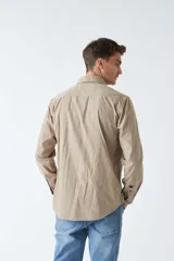 Camisa de pana color beige, de corte regular, con cuello clásico y cierre frontal con botones. Confeccionada en algodón.