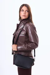 Campera de cuero sintético color negro, con cuello camisero, cierre frontal con cremallera y botones a presión, y bolsillos frontales con solapa.