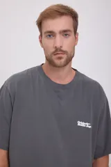 Camiseta gris de manga corta y cuello redondo con estampado pequeño en el pecho.