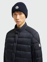 Gorro de lana azul marino con textura acanalada y logo de la marca Moncler bordado en el frente.