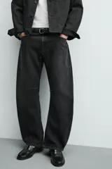 Jeans de denim de algodón en color negro con efecto lavado, corte amplio y silueta curva tipo barrel fit con pinzas en las rodillas. Presenta diseño clásico de cinco bolsillos y cierre frontal con cremallera y botón metálico.