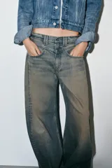 Jeans de tiro bajo con corte baggy y silueta barrel. Presenta diseño de cinco bolsillos, trabillas para cinturón y cierre frontal con cremallera y botón metálico. Confeccionado en denim con efecto de lavado desgastado.