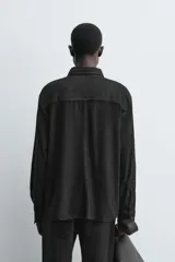 Sobrecamisa de corte regular confeccionada en piel con acabado de ante. Presenta cuello solapa, cierre frontal con botones, manga larga con puños abotonados y un bolsillo de parche en el pecho.