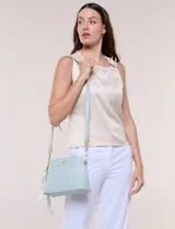 Cartera bandolera estructurada de eco cuero rosado con textura graneada, silueta curva y cierre superior. Posee correa larga regulable con detalles de cadena dorada, bolsillo frontal con logo metálico, pañuelo estampado a contratono anudado en un lateral y base rígida con apoyos metálicos.