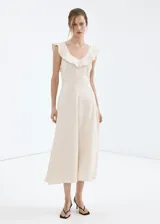 Vestido midi de mezcla de lino y viscosa en color beige, con diseño evasé, cuello en V con volantes decorativos, tirantes anchos y cierre de cremallera lateral.