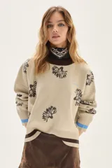 Sweater de punto color bordó con diseño de flores estampadas en tono crema, cuello redondo y puños con detalle de franjas en contraste. Presenta un bordado pequeño en el pecho.