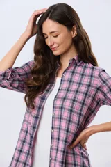 Camisa holgada a cuadros en tonos rosado, azul marino y blanco, de manga larga con puños ajustables, cuello camisero y cierre frontal de botones.
