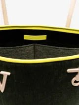Bolso tipo tote de chenilla color verde oscuro con ribete amarillo. Tiene dos correas de hombro color crema, compartimento principal con bolsillos internos y apliques metálicos con el logo de la marca.