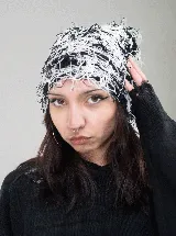 Gorro tipo beanie con diseño de hilos entrelazados en colores blanco y negro, creando un efecto visual texturizado y desmechado.
