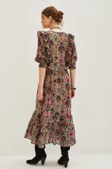 Vestido midi de algodón con estampado floral y geométrico en tonos tierra, fucsia y verde. Presenta escote en V, mangas abullonadas con volados en los hombros y falda con volados en el ruedo.