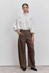 Camisa blanca de cuello alto con volados y mangas abullonadas con puños elásticos.