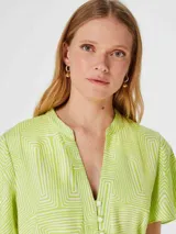 Blusa verde con estampado geométrico blanco, cuello en V y mangas cortas amplias.