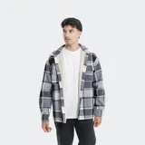 Camisa de franela a cuadros en tonos grises, blancos y negros, forrada con corderito sintético en el interior. Cuenta con mangas largas, bolsillos con solapa en el pecho y cierre frontal con botones.